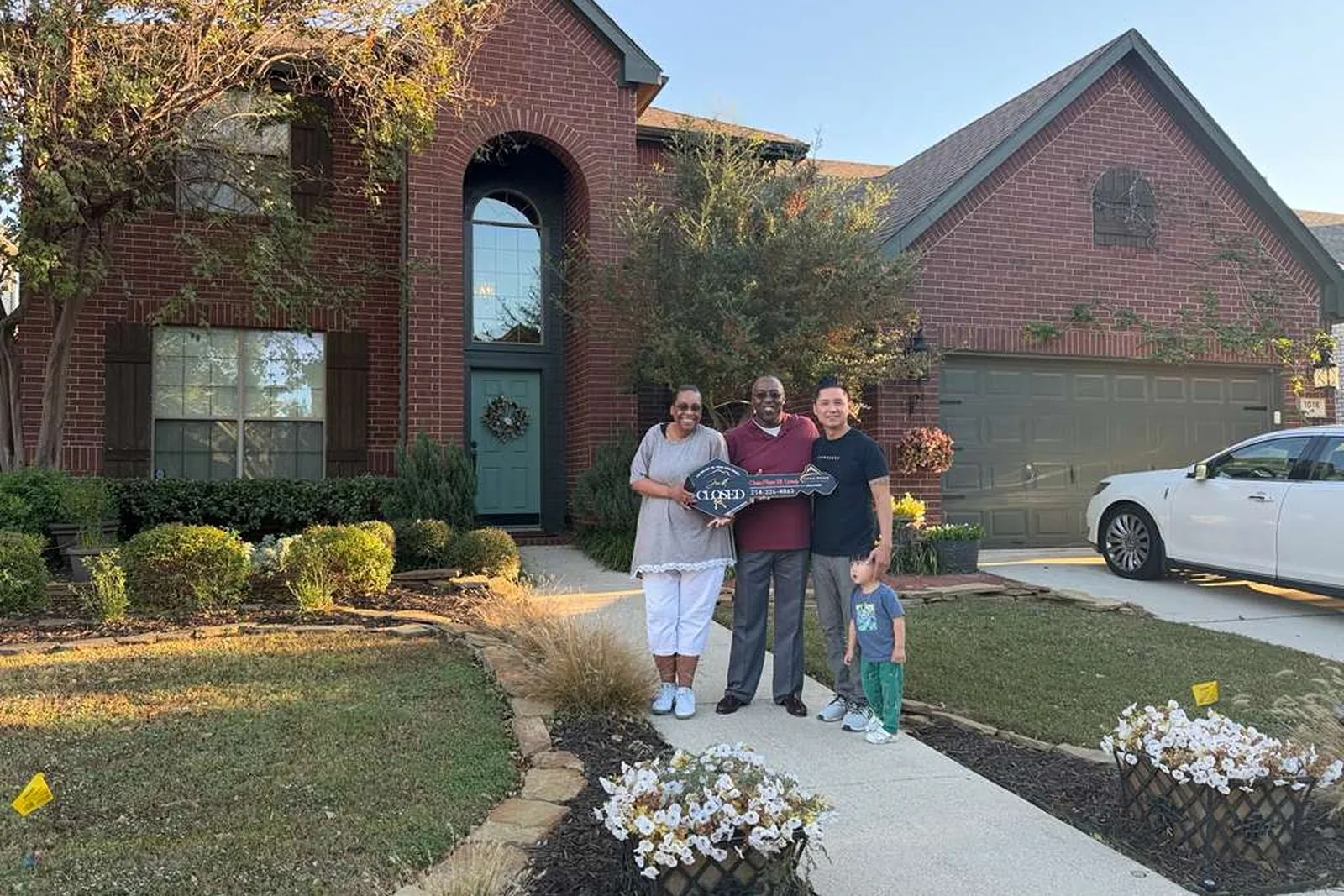 Family celebrating in the driveway of a house bought with a VA home loan in Texas